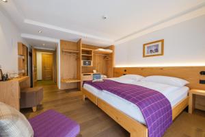 a bedroom with a large bed with a purple blanket at Hotel Bella Vista Zermatt in Zermatt