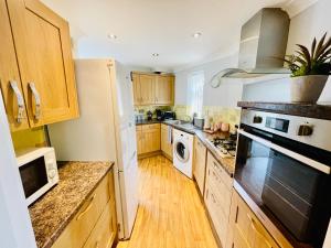 cocina con armarios de madera y horno con fogones en Cozy Bicester Village townhouse with garden en Bicester