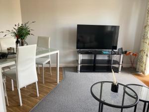a living room with a table and a television at Cozy Bicester Village townhouse with garden in Bicester