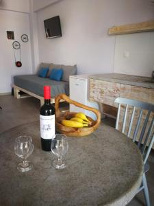 een fles wijn en een mand met bananen op een tafel bij APARTMENTS BY THE SEA in Gázion