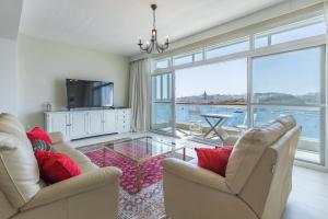uma sala de estar com duas cadeiras e uma grande janela em Stunning - Seafront 3-Bedroom 6th Floor em Sliema