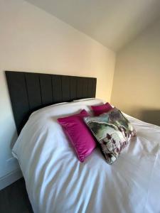 Una cama con dos almohadas rosas encima. en Beautiful Cottage in the Yorkshire Dales, en Leyburn
