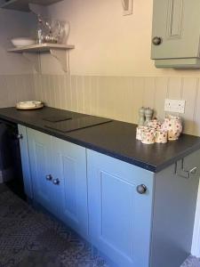 a kitchen with blue cabinets and a black counter top at Beautiful Cottage in the Yorkshire Dales in Leyburn