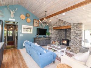 a living room with a blue couch and a stone fireplace at The Owl's Shack in Kendal