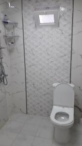 a white bathroom with a toilet and a window at Apartment at Narimanov 151 in Ganja