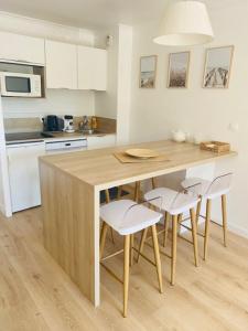 a kitchen with a wooden island with chairs around it at T3 neuf 5 pers Serre Chevalier La Salle les Alpes in La Salle Les Alpes