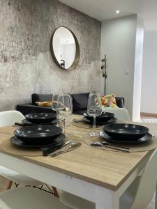 - une table à manger avec des assiettes noires et des verres dans l'établissement La Maison 19 Appartement 4 personnes, à Lens