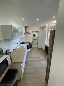 cocina con armarios blancos y suelo de madera en La Maison 19 Appartement 4 personnes en Lens
