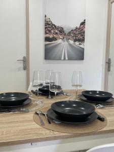 una mesa con platos negros y copas de vino. en La Maison 19 Appartement 4 personnes en Lens