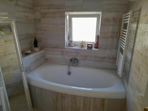 a white bath tub in a bathroom with a window at Pod skálou, Mánesova 646 in Úpice