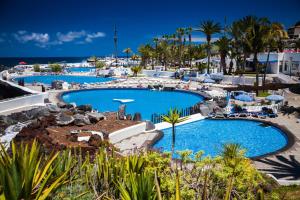 a pool at a resort with palm trees and the ocean at Club Apartments by Grupo Compostelana 1 in Puerto de la Cruz +32 photos
