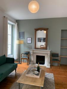 een woonkamer met een groene bank en een open haard bij Grand appartement de Standing #Hypercentre in Cognac