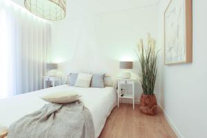 a white bedroom with a bed and a potted plant at Quinta de São Pedro in Barrô