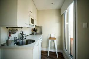 a small white kitchen with a sink and a stool at Apartamentos Cruz in Madrid
