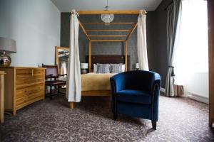 a bedroom with a canopy bed and a blue chair at The Blue Boar in Witney