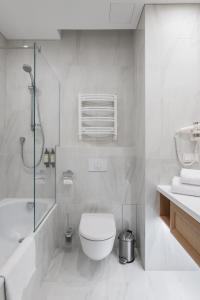 a white bathroom with a toilet and a shower at CALVARY Hotel & Restaurant Vilnius in Vilnius