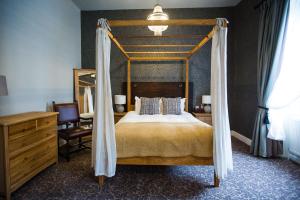 a bedroom with a canopy bed and a desk at The Blue Boar in Witney