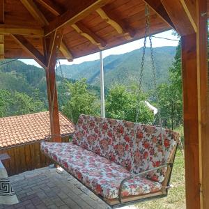 a couch on a porch with a swing at Ljubov kutak in Mokra Gora