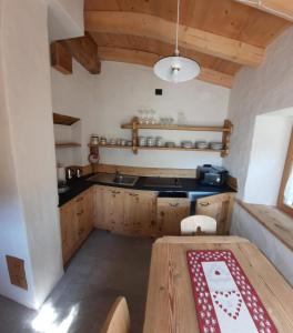 a kitchen with wooden cabinets and a wooden table at Ospitalità Diffusa Laste Dolomites - Cèsa del Bepo Moro in Colle Santa Lucia