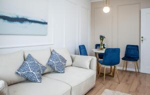 a living room with a white couch and blue chairs at Jaśminowe Wzgórze Apartamenty blisko plaży in Władysławowo
