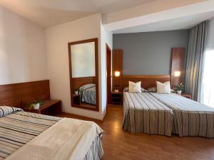 a hotel room with two beds and a mirror at Hotel Alea in El Arenal