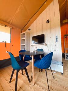 a dining room with blue chairs and a table at camping?glamping morskersweitje in Winterswijk