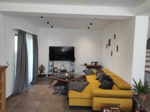 un soggiorno con divano giallo e TV di Casa Nectaria a Moieciu de Jos