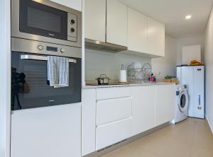 a kitchen with white cabinets and a microwave at Casa de Sao Tiago 1 in Funchal