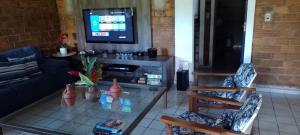 a living room with a couch and a tv at Casa Cantinho da Paz, seu lazer completo, churrasqueira, piscina e muita tranquilidade in Gravatá