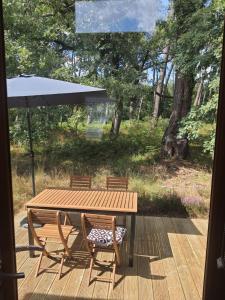 a wooden table with two chairs and an umbrella at Domaine Pinsol in Uchacq-et-Parentis