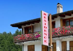 un cartello hotel sul lato di un edificio con fiori di Residence Nube D'Argento a Sestriere