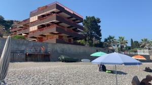 a building on a beach with an umbrella at APPARTAMENTO BLUE HOLIDAY in Letojanni
