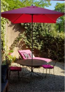 een tafel en stoelen onder een rode paraplu bij Locations Thermaë - Villa Thermaë in Gréoux-les-Bains