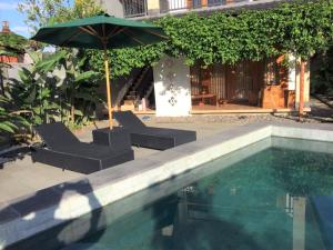 een zwembad met 2 stoelen en een parasol bij Room in Villa - Villa - Warung AromaChampuhan in Mayong