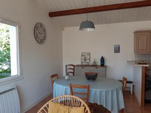 cocina con mesa con sillas y reloj en la pared en Charmante maison de plain pied avec 700m2 de jardin cloturé en Saint-Clément-des-Baleines