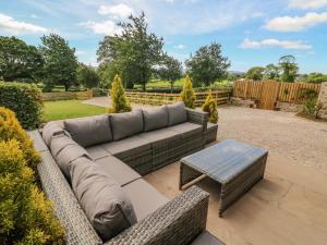 een patio met een bank en een salontafel bij Dairy Cottage in Carnforth