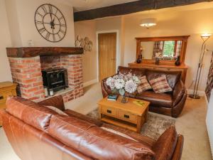 een woonkamer met lederen meubels en een open haard bij Dairy Cottage in Carnforth