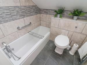 een badkamer met een wit bad en een toilet bij Dairy Cottage in Carnforth +20 foto's