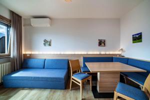 ein Wohnzimmer mit einem blauen Sofa und einem Tisch in der Unterkunft Gartenheim App Maria in Schenna