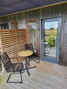 eine Terrasse mit einem Tisch und Stühlen auf einer Veranda in der Unterkunft Bodelssons by the Sea in Tosteberga