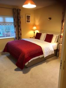 a bedroom with a large bed with a red blanket at Blackrath Farmhouse in Dún Luáin
