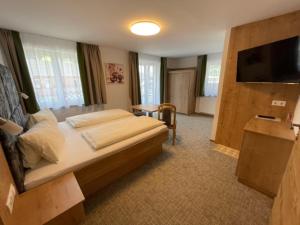 a hotel room with a bed and a flat screen tv at Pension Zum wilden Hannes in Wagrain