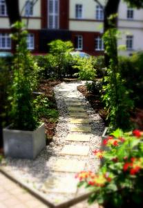 einen Garten mit einem Steinweg mit Blumen und Pflanzen in der Unterkunft SensCity Hotel Berlin Spandau in Berlin