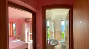 ein Badezimmer mit rosa Wänden, einem Waschbecken und einem Spiegel in der Unterkunft Ligo in Villanova dʼAlbenga