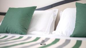 a bed with green and white pillows on it at MIIO HOTEL in San Vincenzo