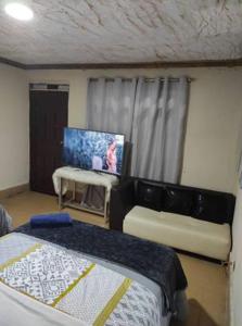 1 dormitorio con cama, mesa y TV en CASA MUY CONFORTABLE EN ZAMORA CHINCHIPE incluye desayuno, en Zamora