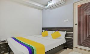 a bedroom with a white bed with yellow and purple pillows at Itsy Hotels Purple Suites in Bengaluru