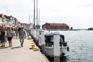 eine Gruppe von Menschen, die auf einem Dock neben einem Boot laufen in der Unterkunft City Harbour House in Sønderborg