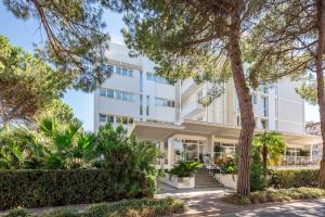 vista esterna di un edificio bianco con alberi di Hotel Bembo a Bibione