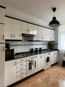 cocina con armarios blancos y lavadora en Apartamento Conde, en Corcubión